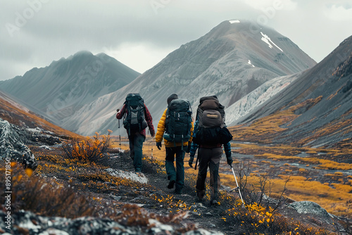 Three people are hiking in the mountains, with backpacks and hiking poles.