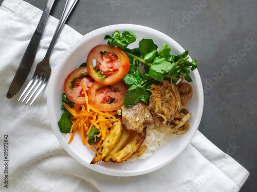 lunchbox in styrofoam pot with watercress salad, rice, pork and rustic potatoes and rustic background