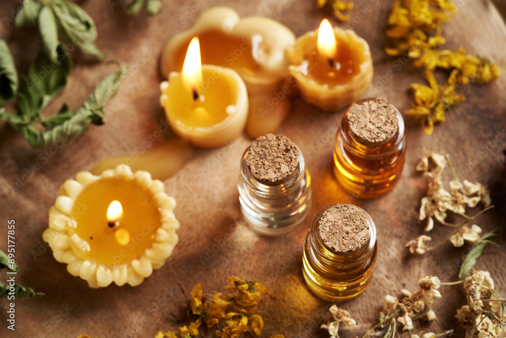 Three bottles of aromatherapy essential oils with dried herbs and flowers and beeswax candles Three bottles of aromatherapy essential oils with dried herbs and flowers and beeswax candles