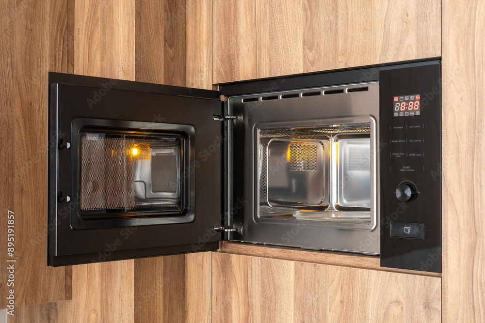 Fototapeta premium Black microwave oven with open door in modern kitchen