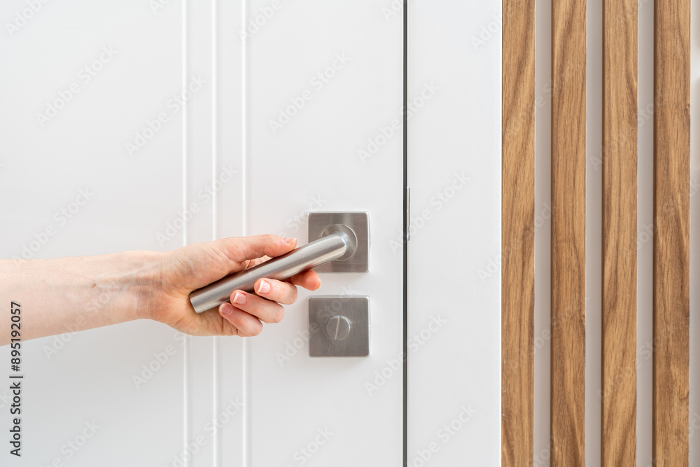 Hand holding silver handle and opening door in room Hand holding silver handle and opening door in room