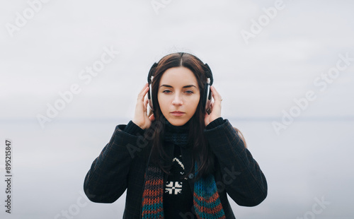 A young Caucasian girl wearing headphones listens to her favorite music and looks carefully into the distance. Mood. Radio concept. Copy space. photo