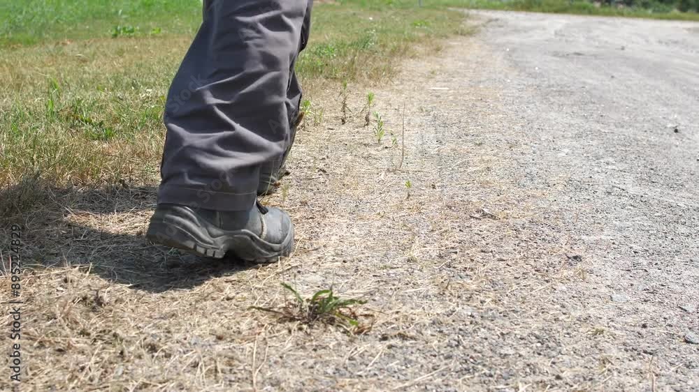 close-up of the legs of a man in boots walking along a rural road close-up of the legs of a man in boots walking along a rural road