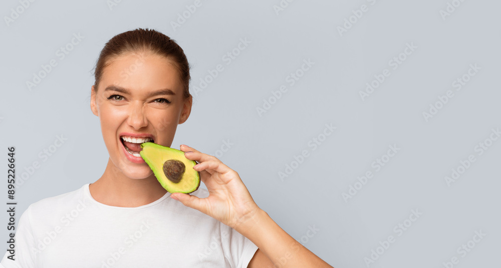 Playful Woman Biting Avocado Half Smiling To Camera Posing Over White Studio Background. Panorama, Free Space Playful Woman Biting Avocado Half Smiling To Camera Posing Over White Studio Background. Panorama, Free Space
