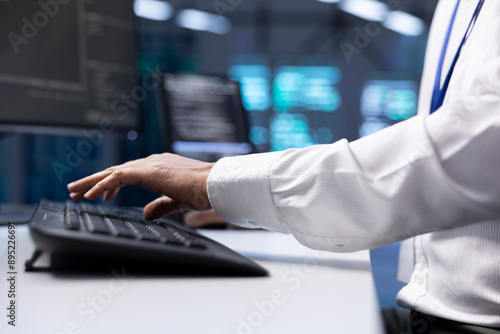 Software developer in data center checking equipment performance on computer after upgrading hardware. Close up shot of IT worker doing maintenance on storage devices in servers farm
