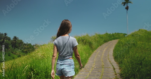 фотографія Girl walking green field asian Bali landscape in sunny day