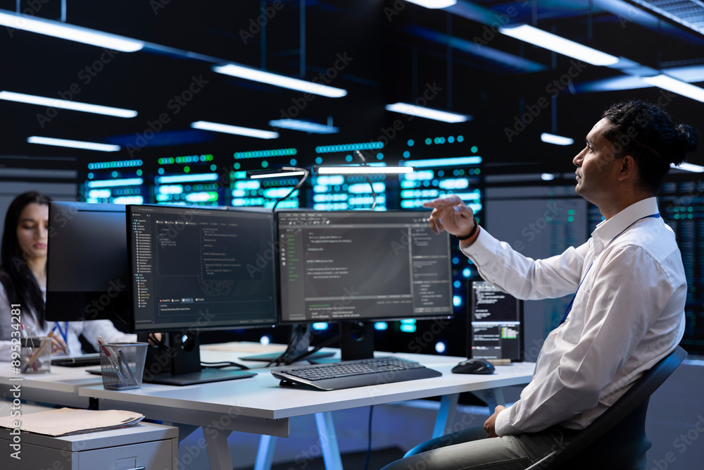 System administrator looking at holograms in data center, monitoring equipment. IT staff member in server farm interacting with futuristic augmented reality AI visualization System administrator looking at holograms in data center, monitoring equipment. IT staff member in server farm interacting with futuristic augmented reality AI visualization