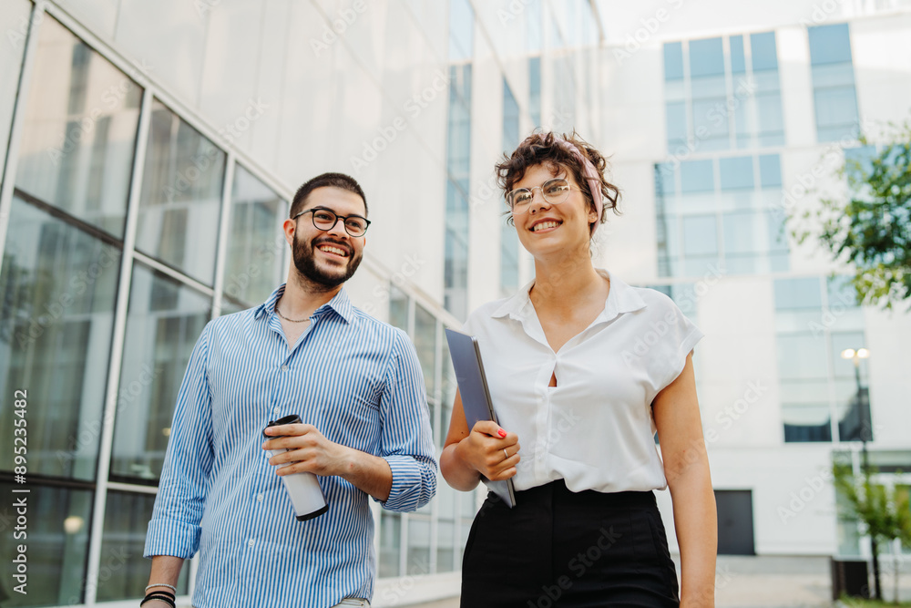 Two smiling business people going to work to modern business building Two smiling business people going to work to modern business building