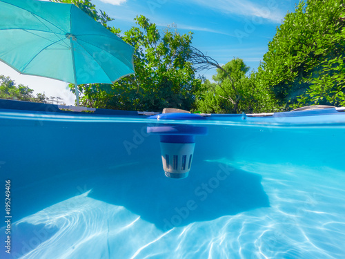 Split underwater view of a chlorine dispenser floating in a pool