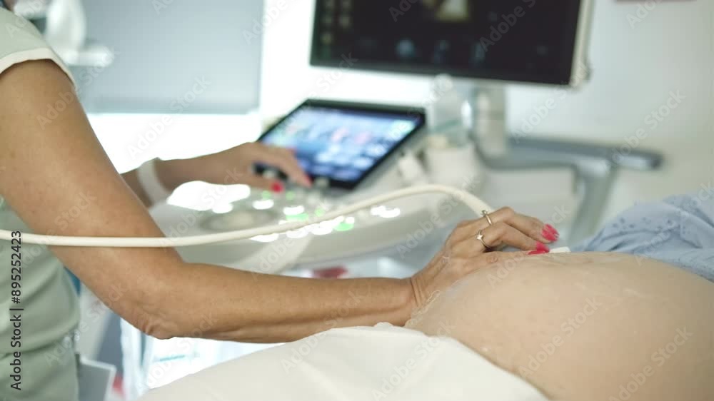 Doctor holds transducers examining pregnant patient using ultrasound equipment. Future mother undergoes regular prenatal checkup in clinic Doctor holds transducers examining pregnant patient using ultrasound equipment. Future mother undergoes regular prenatal checkup in clinic