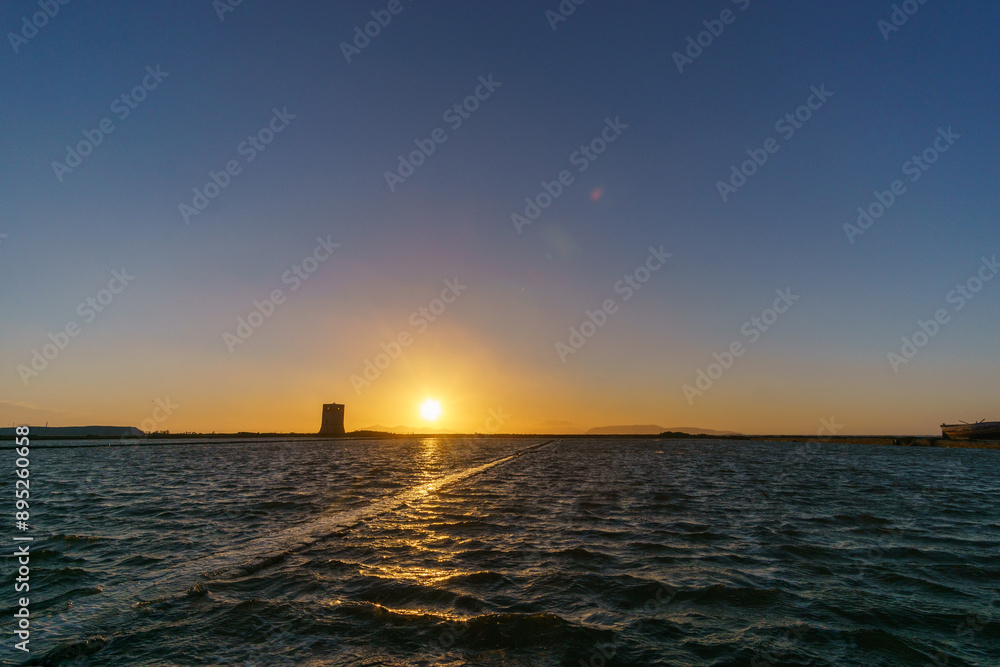 Fototapeta premium Sunset at tower of Nubia in nature reserve of Saline di Trapani with salt fields, Contrada Nubia, Sicily, Italy