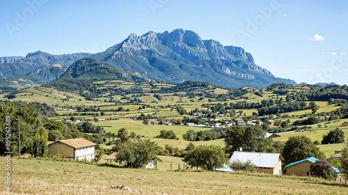 A picturesque village in the Pyrenees Mountains, with rolling hills, green fields, and charming houses. The majestic mountains rise in the background, offering a breathtaking view