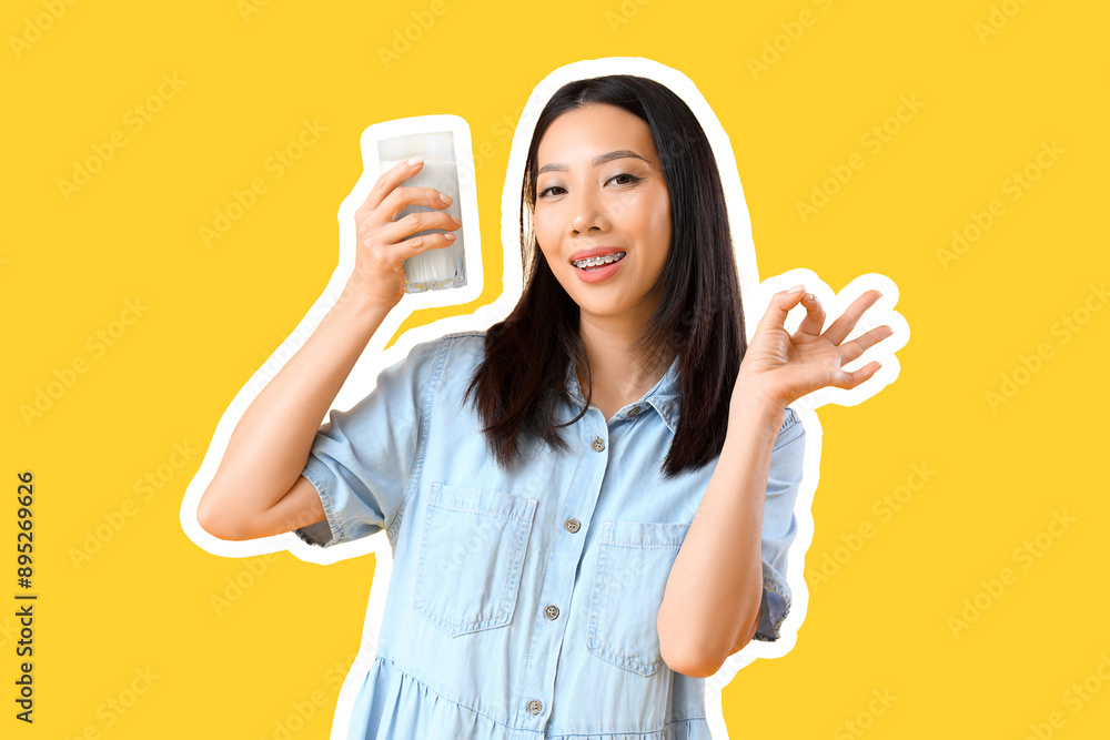Young Asian woman with glass of milk showing OK on yellow background Young Asian woman with glass of milk showing OK on yellow background
