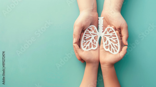 The hands of an adult and child holding paper cutouts in the shape of lungs on a light blue background