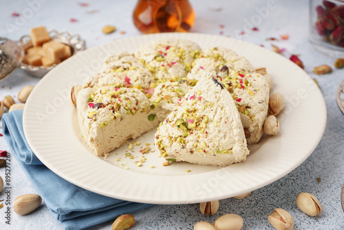 Plate of tasty Tahini halva with pistachios on light background photo