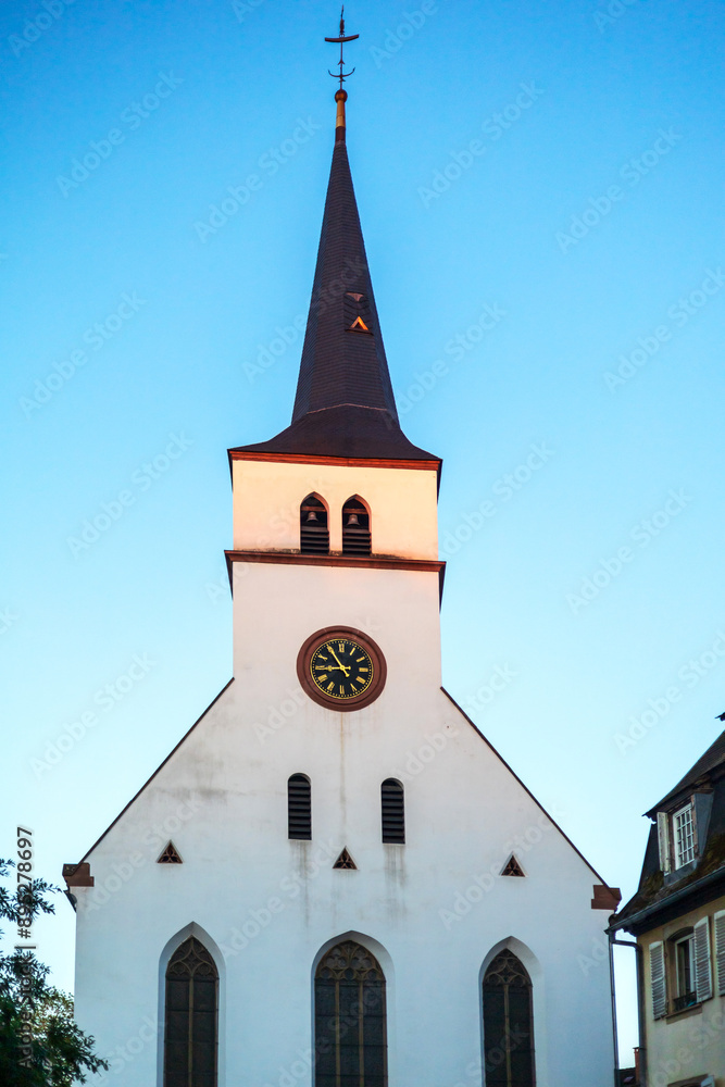 Fototapeta premium A serene view of a Gothic church tower with a clock in Strasbourg during sunset