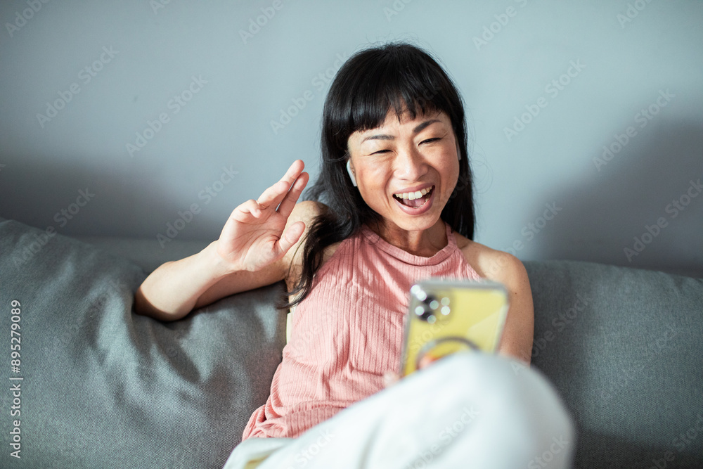Smiling Asian woman using smartphone at home Smiling Asian woman using smartphone at home