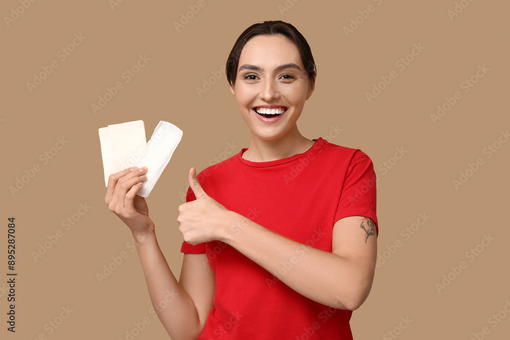 Beautiful young woman with menstrual pads on brown background Beautiful young woman with menstrual pads on brown background