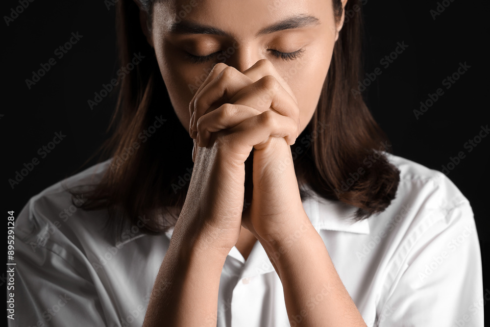Young woman praying on black background, closeup Young woman praying on black background, closeup