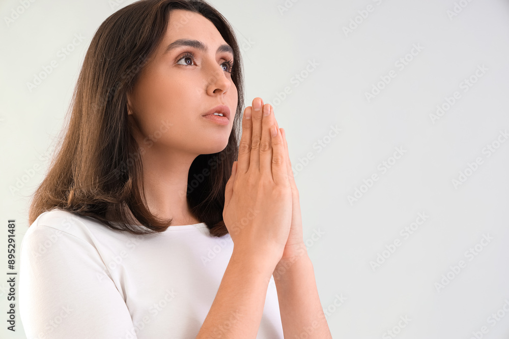 Young woman praying on light background, closeup Young woman praying on light background, closeup