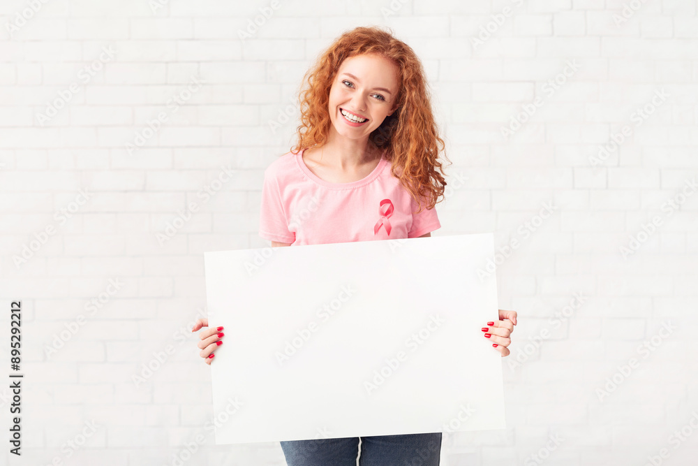 Breast Cancer. Young Woman Holding Blank Poster For Text Wearing Pink T-Shirt With Ribbon Over White Wall Indoors. Breast Cancer. Young Woman Holding Blank Poster For Text Wearing Pink T-Shirt With Ribbon Over White Wall Indoors.
