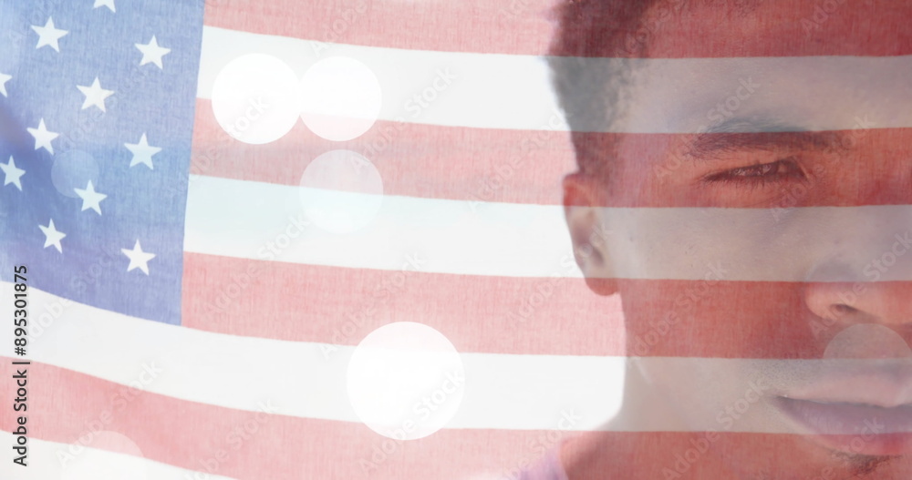 Naklejka premium Image of american flag and light spots over half portrait of happy biracial man on sunny beach