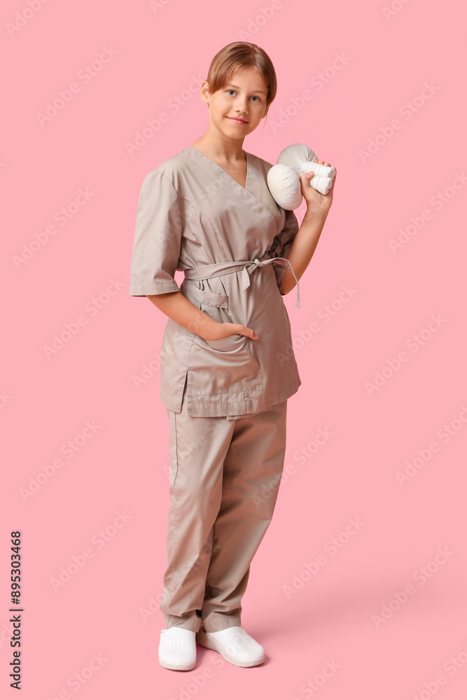 Portrait of teenage massage therapist with herbal bags on pink background