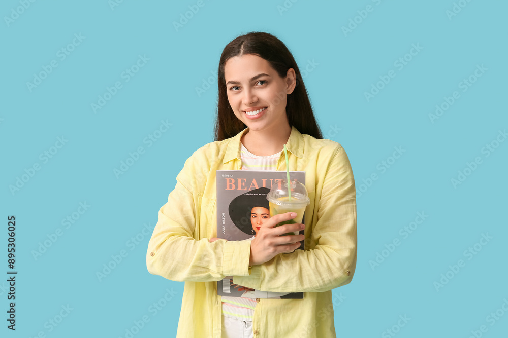 Beautiful young happy woman with cup of fresh lemonade and magazine on blue background Beautiful young happy woman with cup of fresh lemonade and magazine on blue background