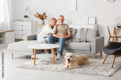 Mature couple with Labrador dog sitting on sofa at home