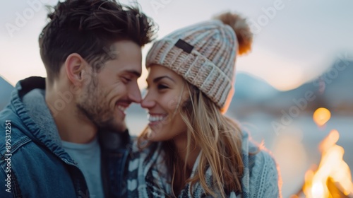 Youthful couple dressed warmly enjoying an outdoor bonfire together, capturing a moment of closeness, warmth, and love in a serene natural setting with a cozy atmosphere. photo