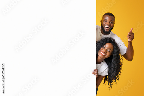 Canvastavla A couple smiles and gives a thumbs up as they peek around a corner against a bright yellow background