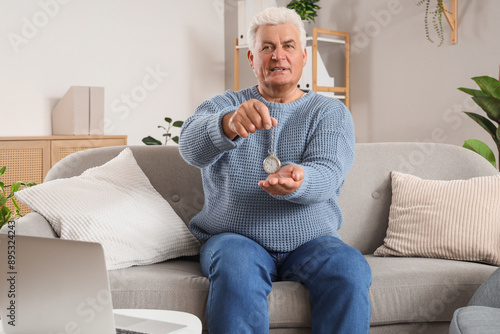 Male hypnotist with pocket watch sitting on sofa in office