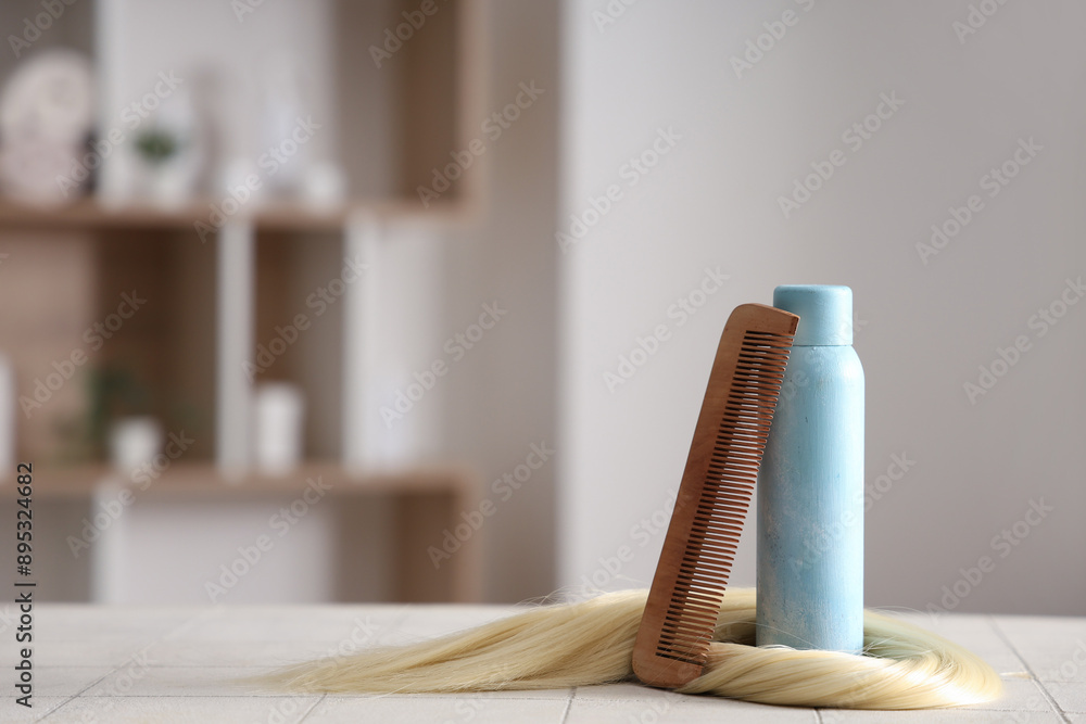 Naklejka premium Hair spray with strand and comb on table in beauty salon