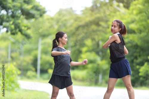 Two sisters are warming up before exercising in the park