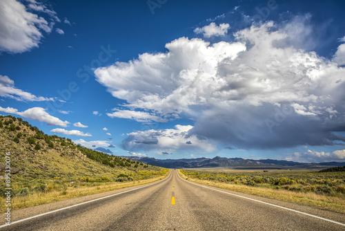 Autumnal view of asphalt road in the desert against land horizon and mountain with blue sky, California, USA 