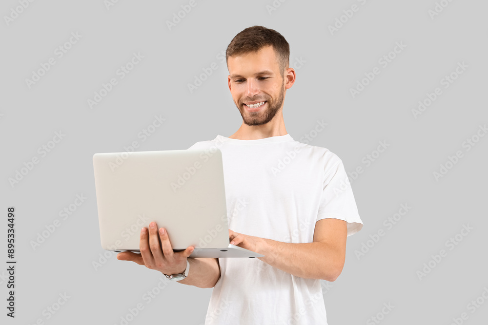Handsome man using laptop on light background Handsome man using laptop on light background