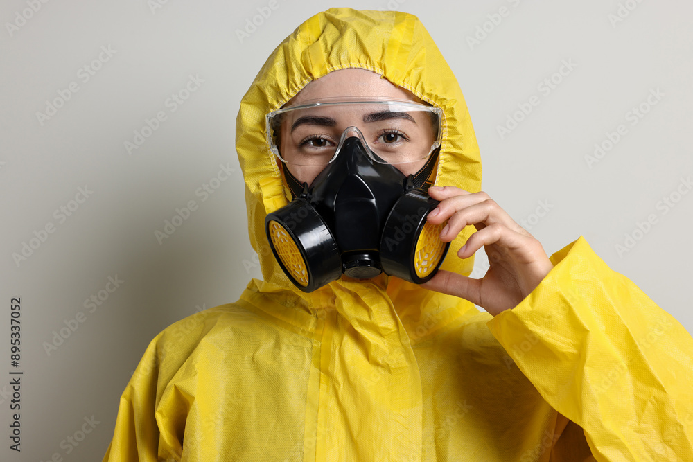 Worker in respirator, protective suit and glasses on grey background Worker in respirator, protective suit and glasses on grey background