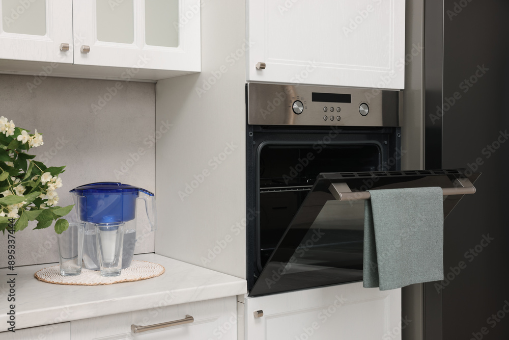 Fototapeta premium Open electric oven with towel in kitchen. Cooking appliance