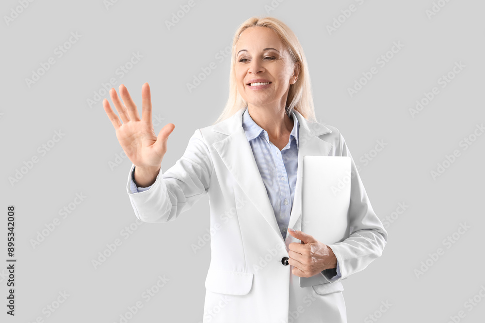 Mature businesswoman with laptop using virtual screen on light background Mature businesswoman with laptop using virtual screen on light background
