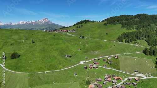 Flying above green mountain slope meadow and small village, Switzerland photo