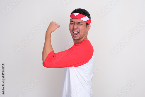 Indonesian man showing his arm muscle with enthusiastic expression photo