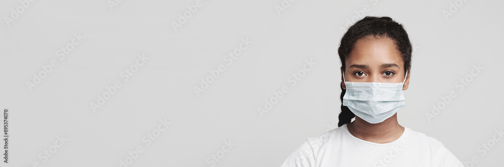 Flu concept. Teen african girl with protective face mask, grey studio background Flu concept. Teen african girl with protective face mask, grey studio background