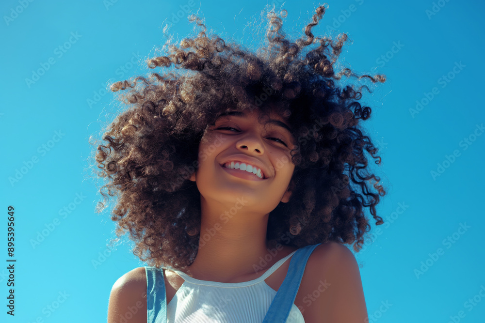 An African American young woman with afro hair smiling outdoors