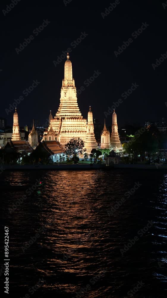 Vertical video, Wat Arun Ratchawararam Ratchaworamahawihan. At night along the Chao Phanaya River, Bangkok, Thailand, There is a boat moving in the river. Vertical video, Wat Arun Ratchawararam Ratchaworamahawihan. At night along the Chao Phanaya River, Bangkok, Thailand, There is a boat moving in the river.