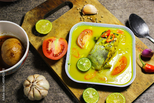 Ikan patin kuah kuning or catfish cooked in yellow sauce. Indonesian dishes have a savory and spicy taste photo