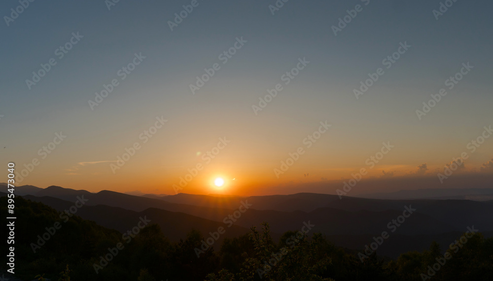 Sunset over distant hills with clear sky. Sunset over distant hills with clear sky.