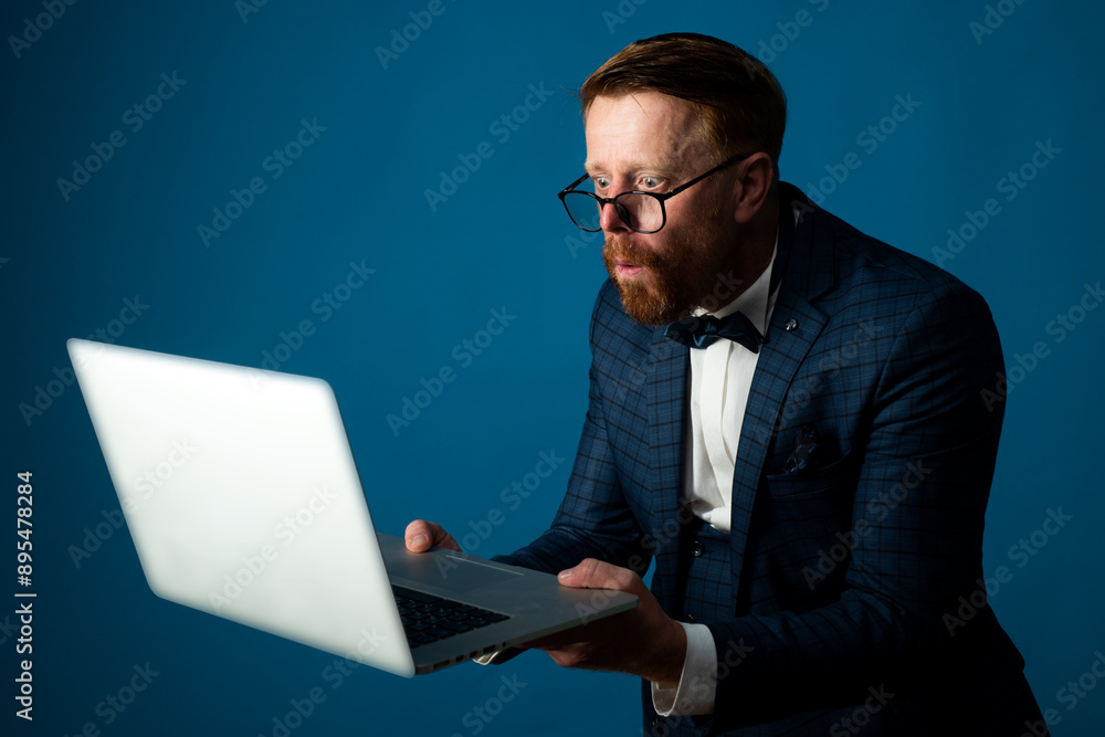 Funny Business man using laptop in studio. Searching job online, shopping online. Crazy businessman working online with a laptop isolated on blue studio. Funny Business man using laptop in studio. Searching job online, shopping online. Crazy businessman working online with a laptop isolated on blue studio.