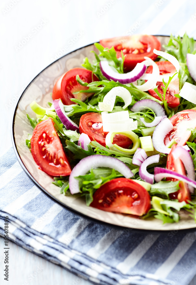 Salad with fresh tomatoes and arugula on a bright stone background. Close up. Copy space. Salad with fresh tomatoes and arugula on a bright stone background. Close up. Copy space.