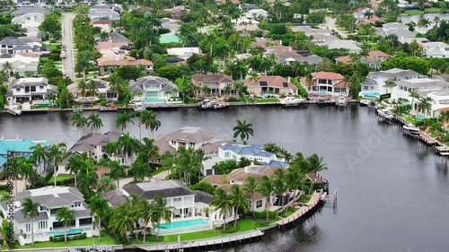 Waterfront homes with private docks in Florida. Lush greenery and palm trees surround luxury properties. Canal view, aerial. photo