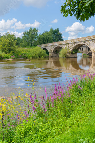 Atcham bridge from the banks of the fast flowing River Severn in Atcham, Shropshire, UK on a summer's day in portrait orientation